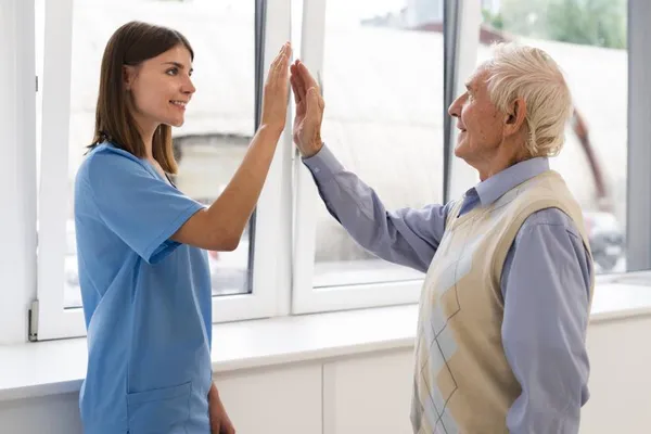 Pflegerin und älterer Mann beim High-Five