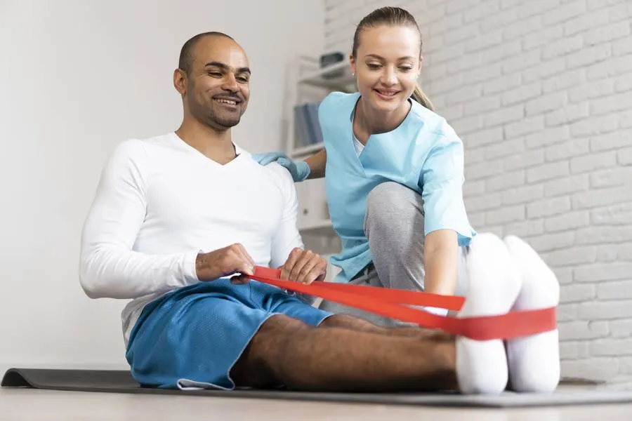 Physiotherapeutin übt mit einem Mann am Band